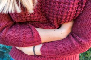 Reizdarm macht Schmerzen Junge Frau verschränkt Arme vor dem Bauch